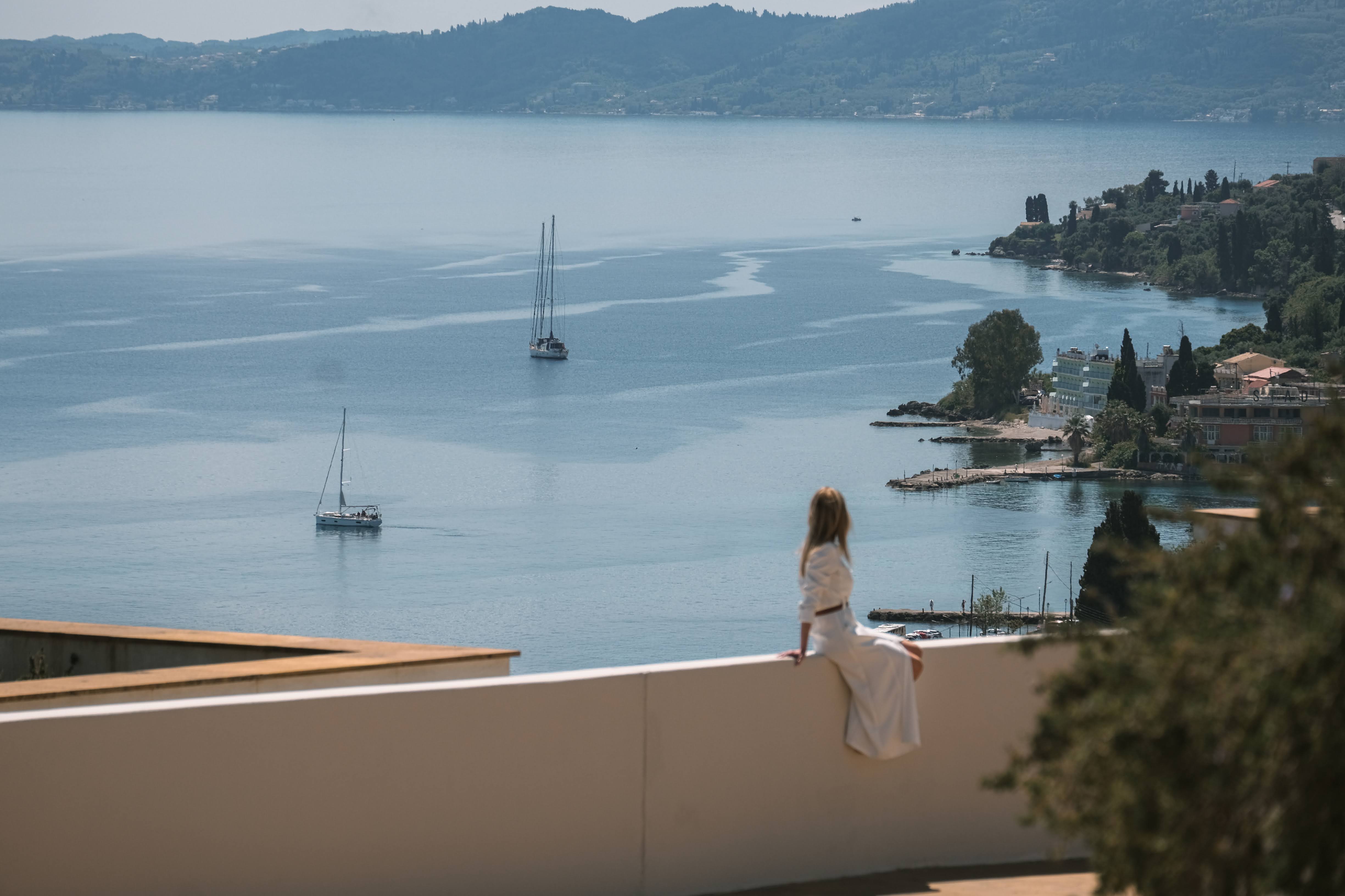 woman looking at benitses village in corfu from above